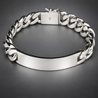 A silver-tone metal bracelet with a smooth central ID plate and a curb chain link design, shown on a dark background.