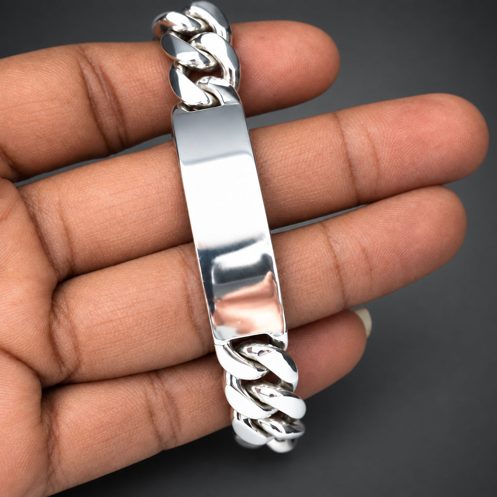 Silver bracelet with intricate design held in a hand against a dark gray background