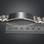 Silver bracelet with a ruler for scale on a dark background