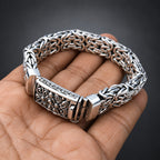 Silver and rose gold bracelet on a hand with a dark background