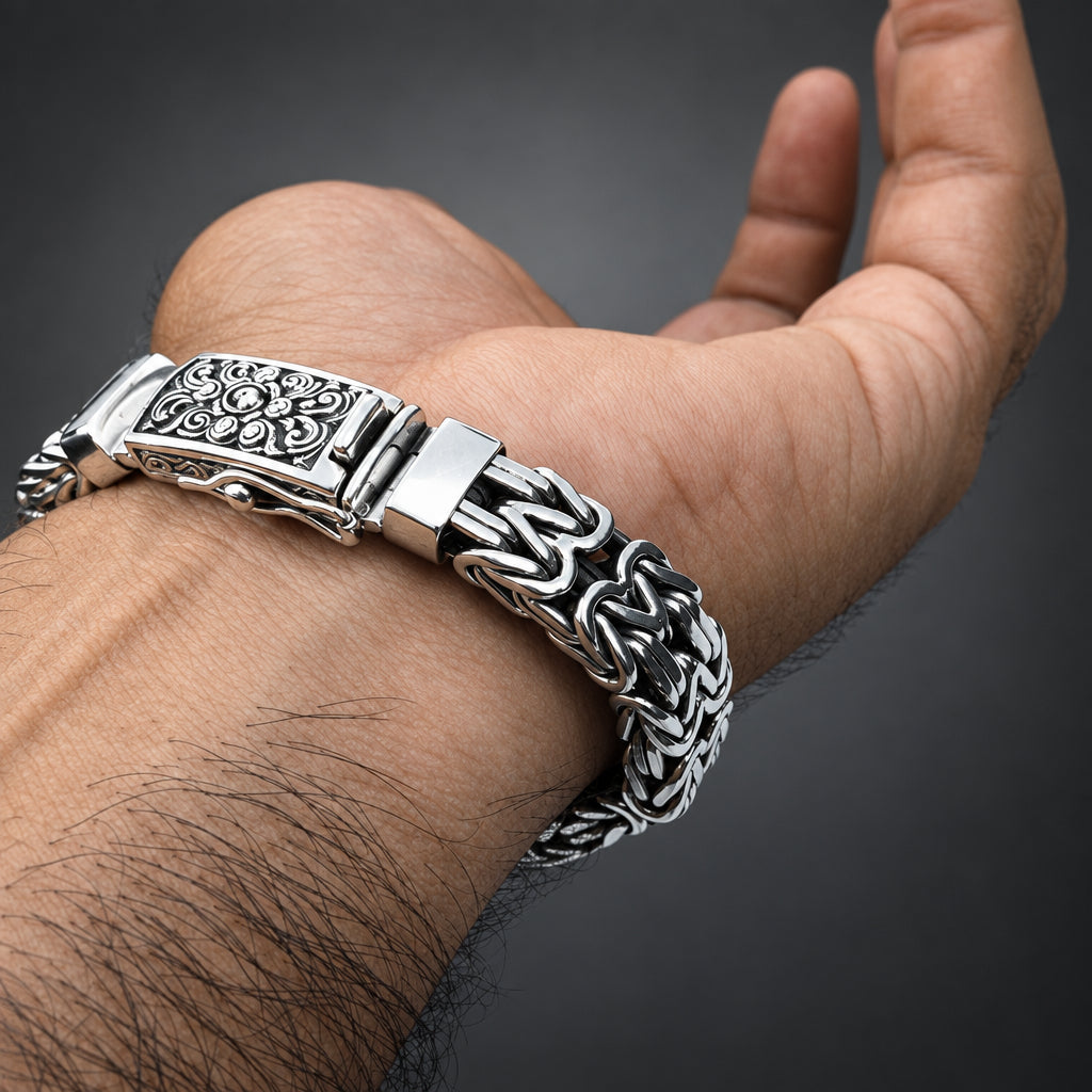 Silver bracelet with intricate design on a wrist against a gradient dark grey background