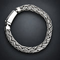 Silver braided bracelet on a hand with a gradient dark grey background