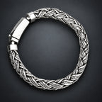 Silver braided bracelet on a hand with a gradient dark grey background