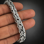 Silver braided bracelet on a hand against a plain background