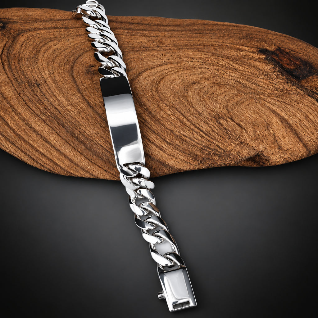A silver Cuban link chain ID bracelet with a polished rectangular nameplate, displayed diagonally on a rustic wood slice over a white background.