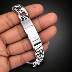 Silver bracelet held in a hand against a dark background