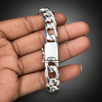 Silver chain bracelet held in a hand against a plain background