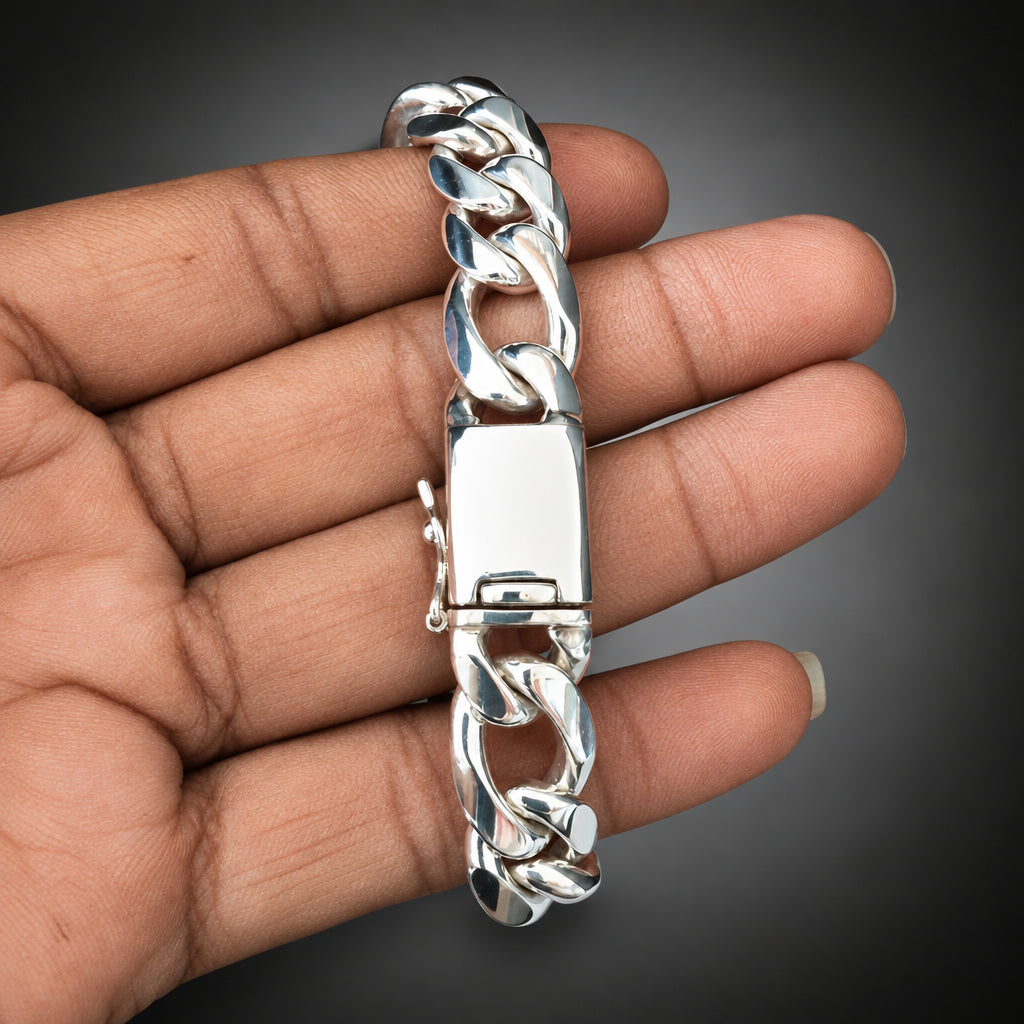 Silver chain bracelet held in a hand against a plain background
