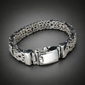 Silver bracelet with a textured band on a wooden surface