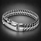 A silver-toned metal bracelet with a curb-style chain link design and a polished clasp, photographed on a plain dark background.