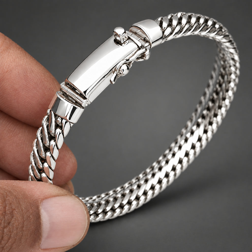 Silver bracelet held by a hand on a light background