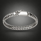A silver-toned metal chain-link bangle bracelet held by a hand against a plain light gray background.