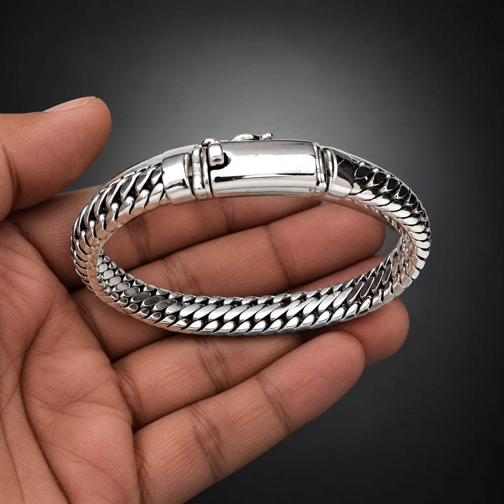 Silver bracelet held by a hand on a light gray background