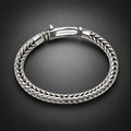 A silver braided cable bracelet with a polished clasp, displayed on a dark gray gradient background.