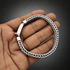 Silver braided bracelet on a hand against a light background