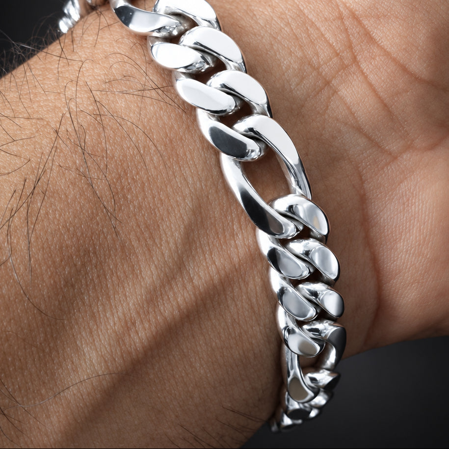 A close-up of a polished silver Cuban link chain bracelet worn on a person's wrist.