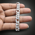 A silver Cuban link chain bracelet held vertically against a person's hand, showing its polished metallic links and dark gray gradient background.