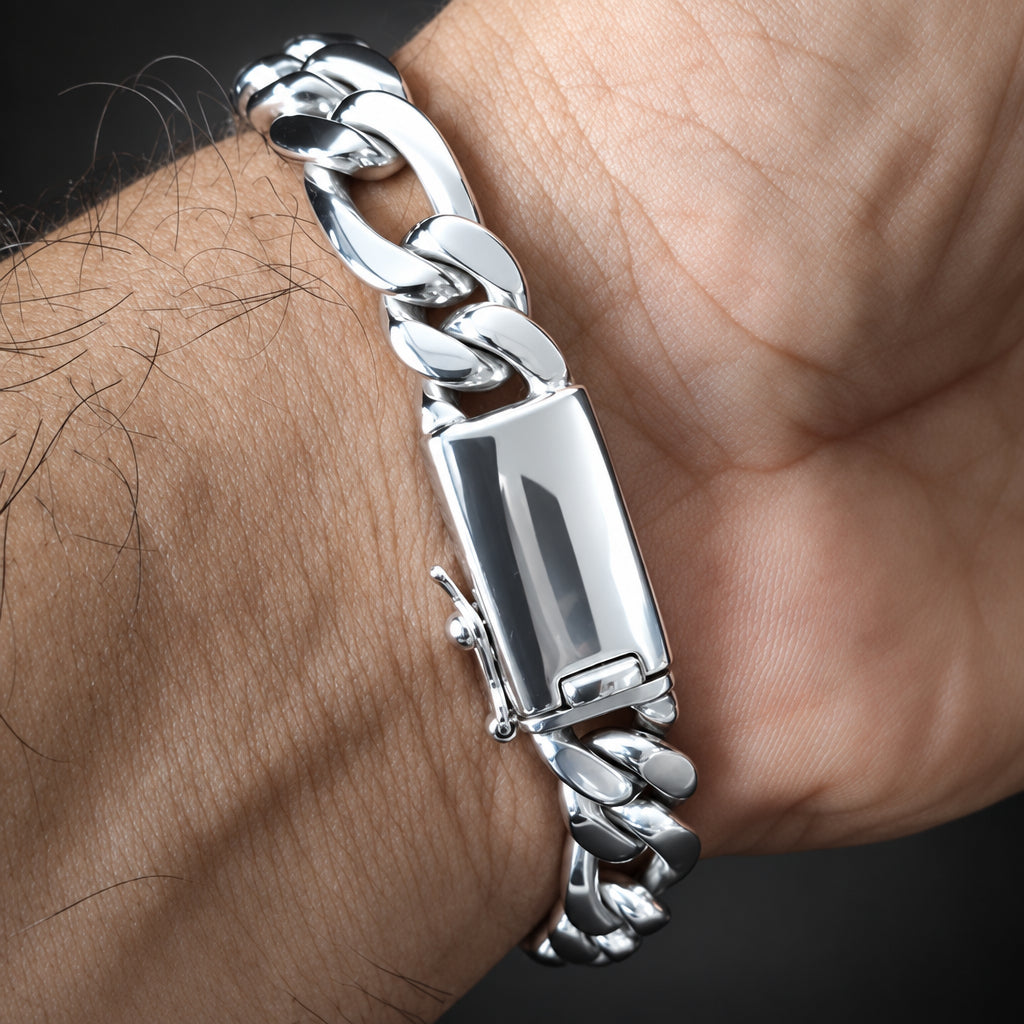 A close-up of a silver-toned chunky chain bracelet with a rectangular clasp, worn on a person's wrist against a dark background.