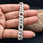 A silver Cuban link chain bracelet held on a person's fingers against a dark background with a wood slice prop.