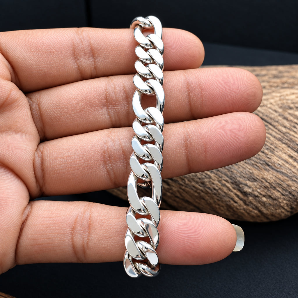 A silver Cuban link chain bracelet held on a person's fingers against a dark background with a wood slice prop.