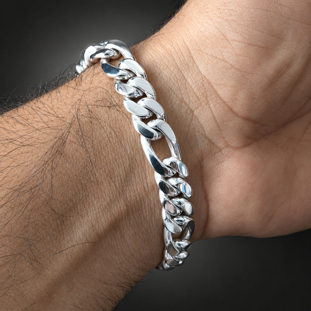 A close-up of a polished silver Cuban link bracelet worn on a person's wrist against a dark gray background.