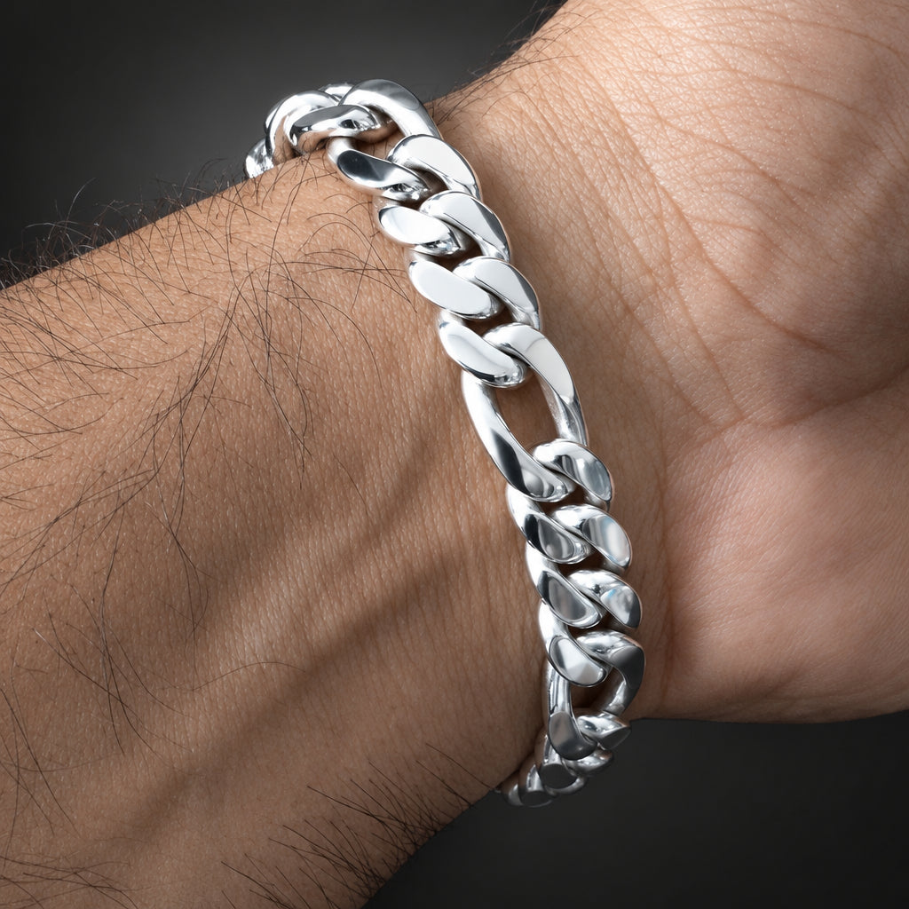 A polished silver Cuban link chain bracelet worn on a person's wrist, shown in a close-up shot against a dark background.