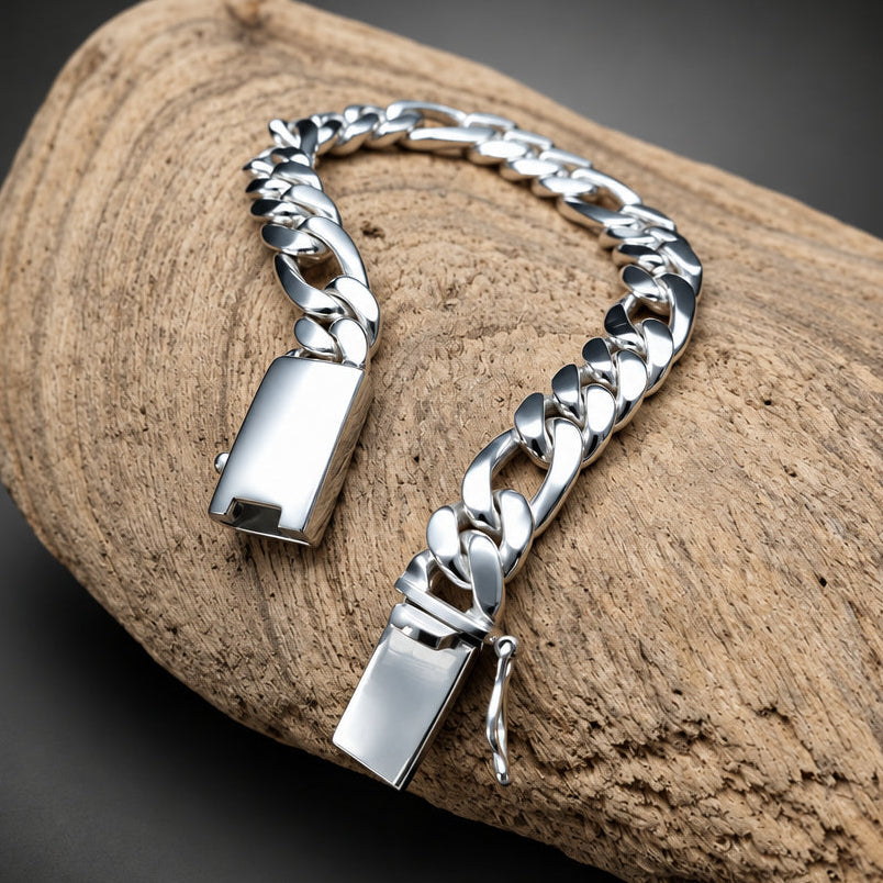 A silver Cuban link chain bracelet with polished rectangular clasps, displayed on a textured piece of driftwood against a dark gray background.
