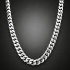 A polished silver-tone Cuban link chain necklace draped in a U-shape over a light brown wooden surface.