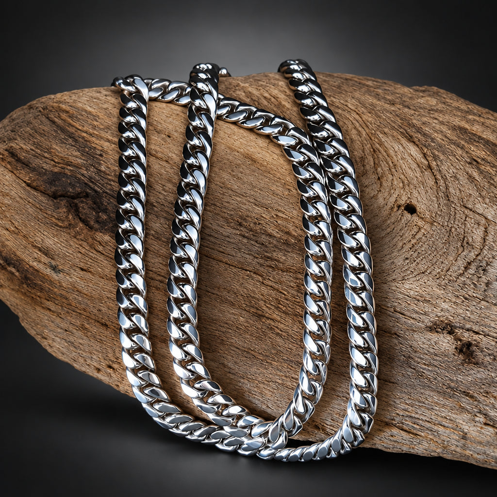 A chunky silver-tone Cuban link chain draped over a curved piece of natural wood against a black background.