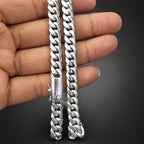 Silver chain held by a hand against a dark background