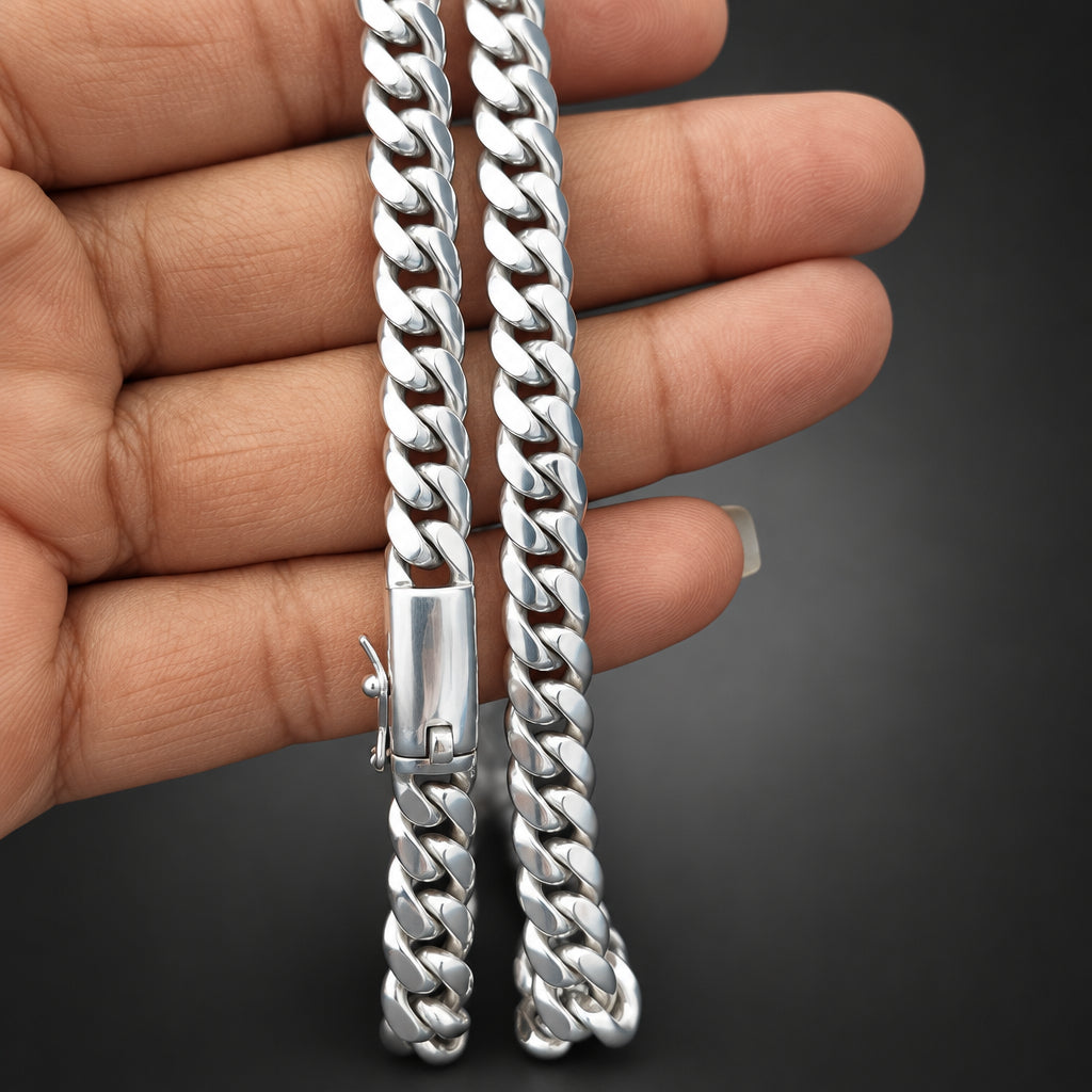 Silver chain held by a hand against a dark background