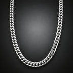 A silver-toned Cuban link chain necklace arranged in a U-shape against a dark gray gradient background.