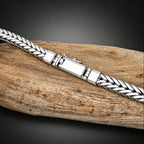 Silver braided bracelet on a wooden surface with a black background