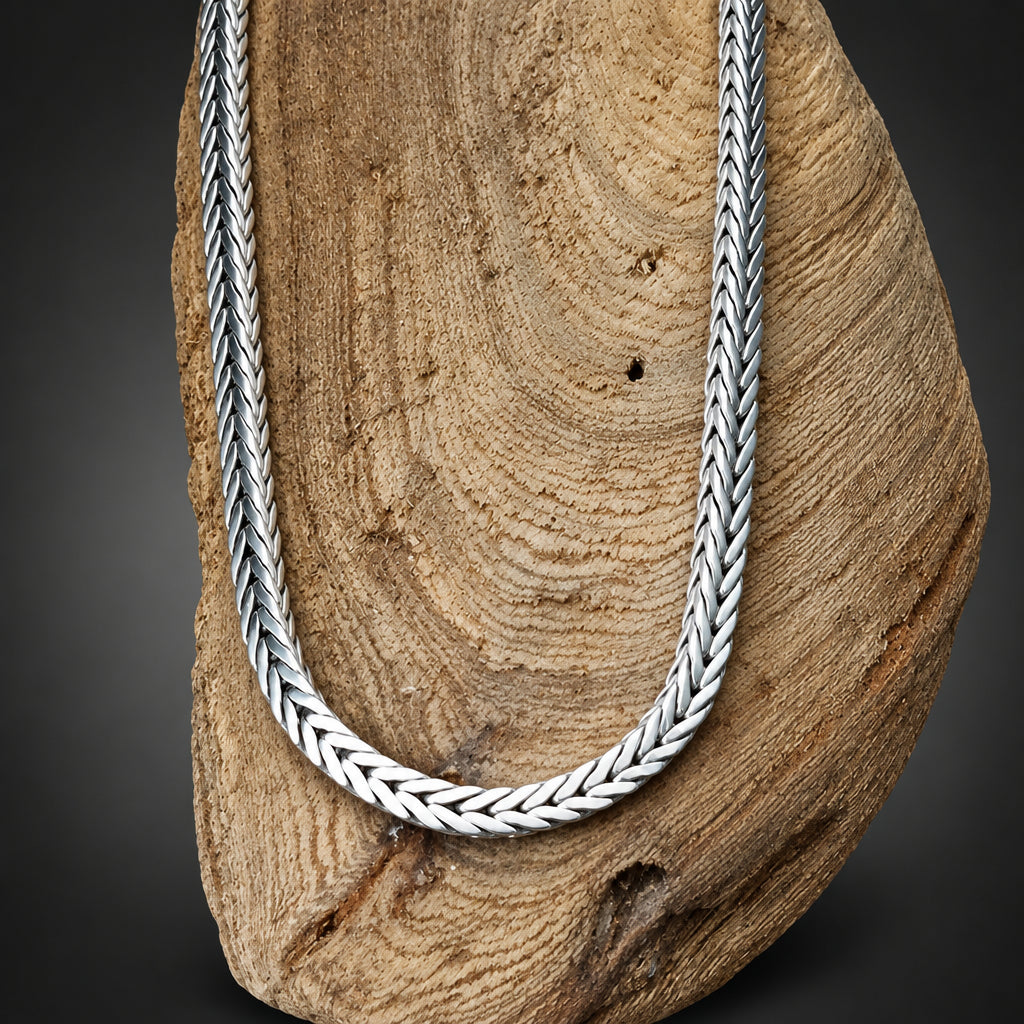 Silver braided necklace on a wooden surface
