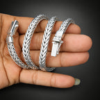 Three silver bracelets on a hand with a dark background
