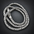 Silver braided necklace on a hand with a wooden background