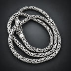 Silver braided necklace on a hand with a wooden background