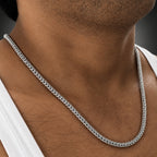 Silver chain necklace on a person's neck with a blurred background