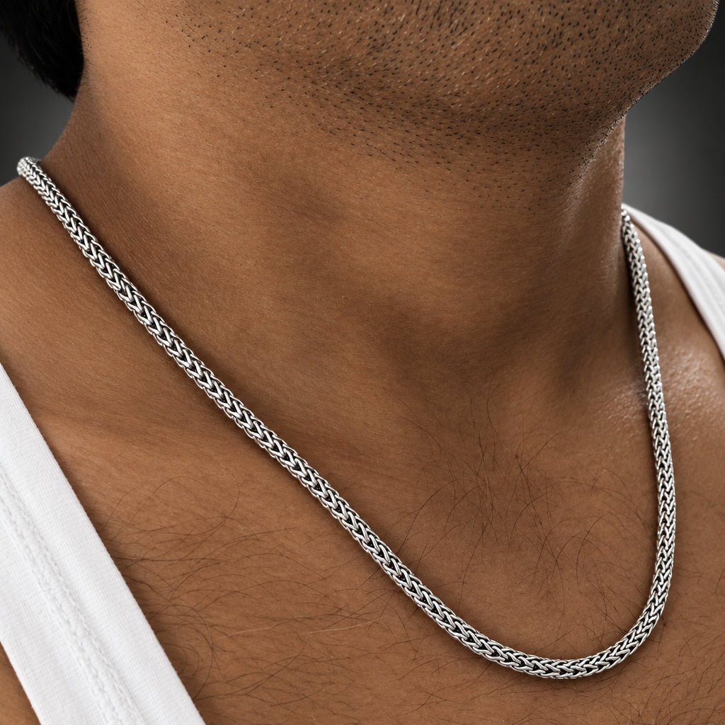 Silver chain necklace on a person's neck with a blurred background
