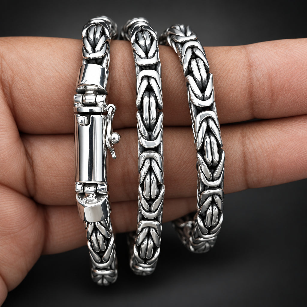 Silver bangles with intricate designs on a hand against a dark background