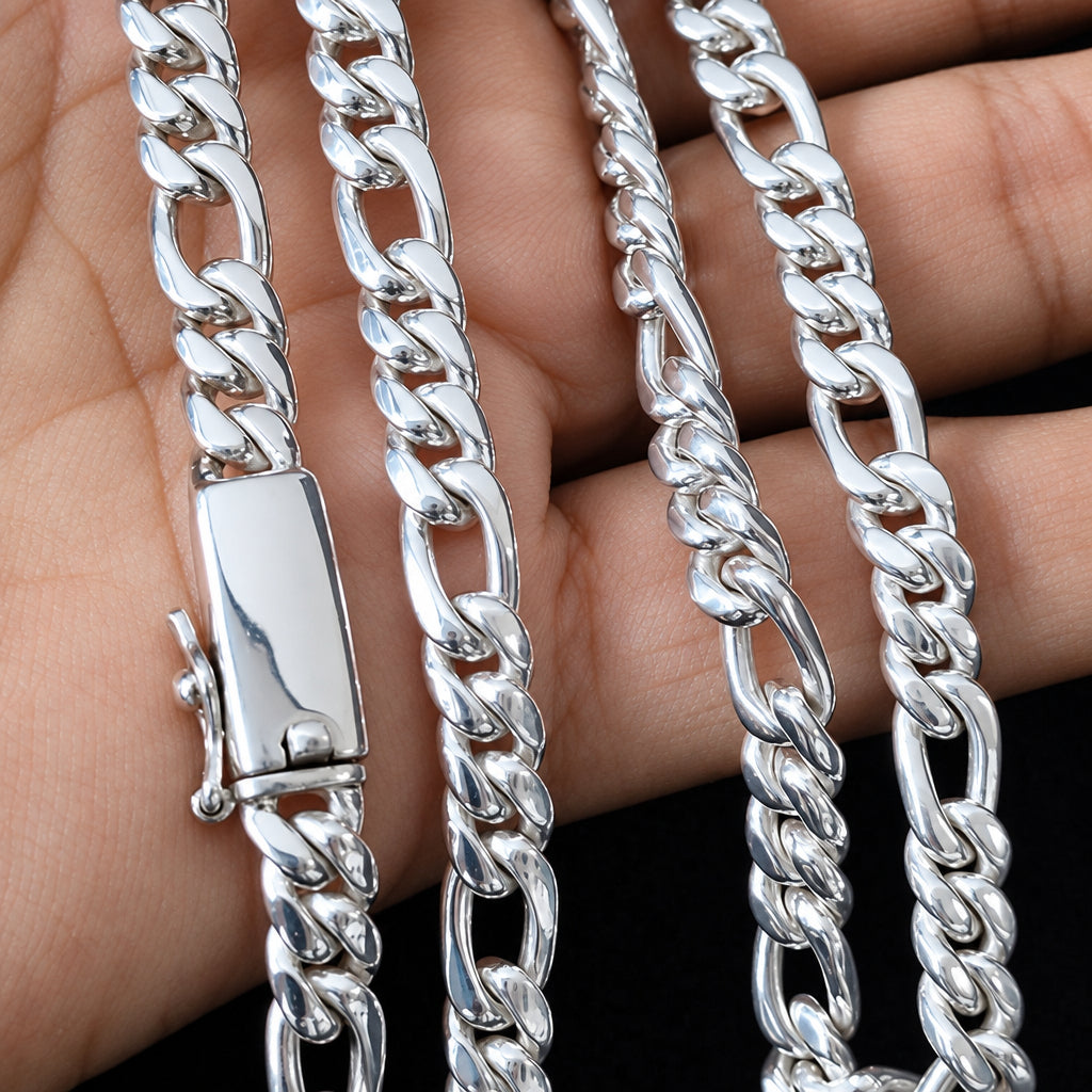 A close-up of a silver-toned metal chain necklace draped over a person's hand, showing the curb-style links and a polished clasp against a dark background.