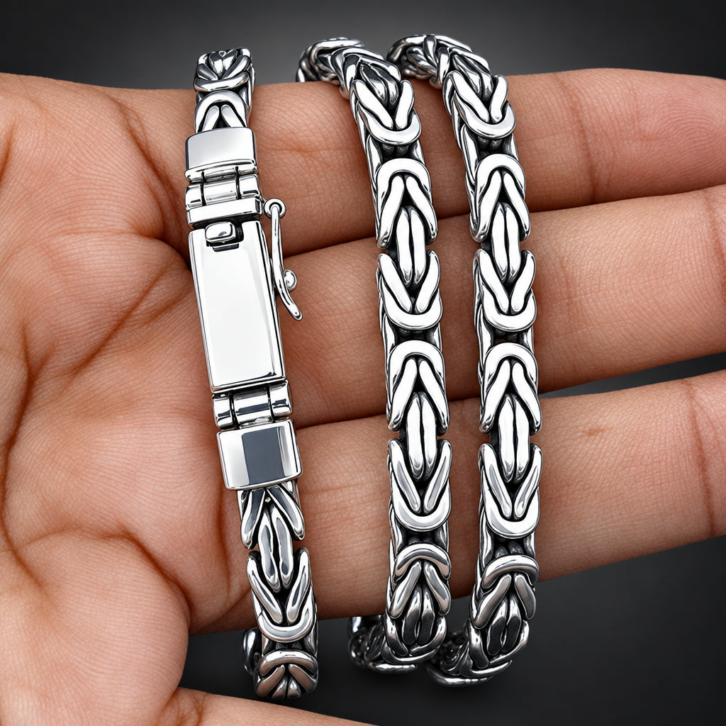 A silver-toned chain bracelet with a textured, interlocking link design, displayed on a person's hand against a black background.
