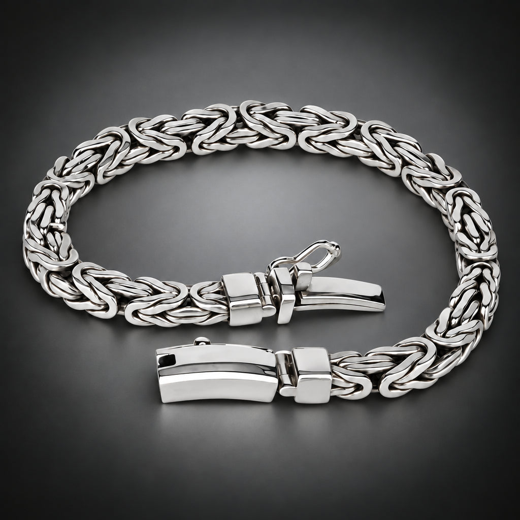 A silver-toned braided chain bracelet with a polished rectangular clasp, displayed on a dark gray gradient background.
