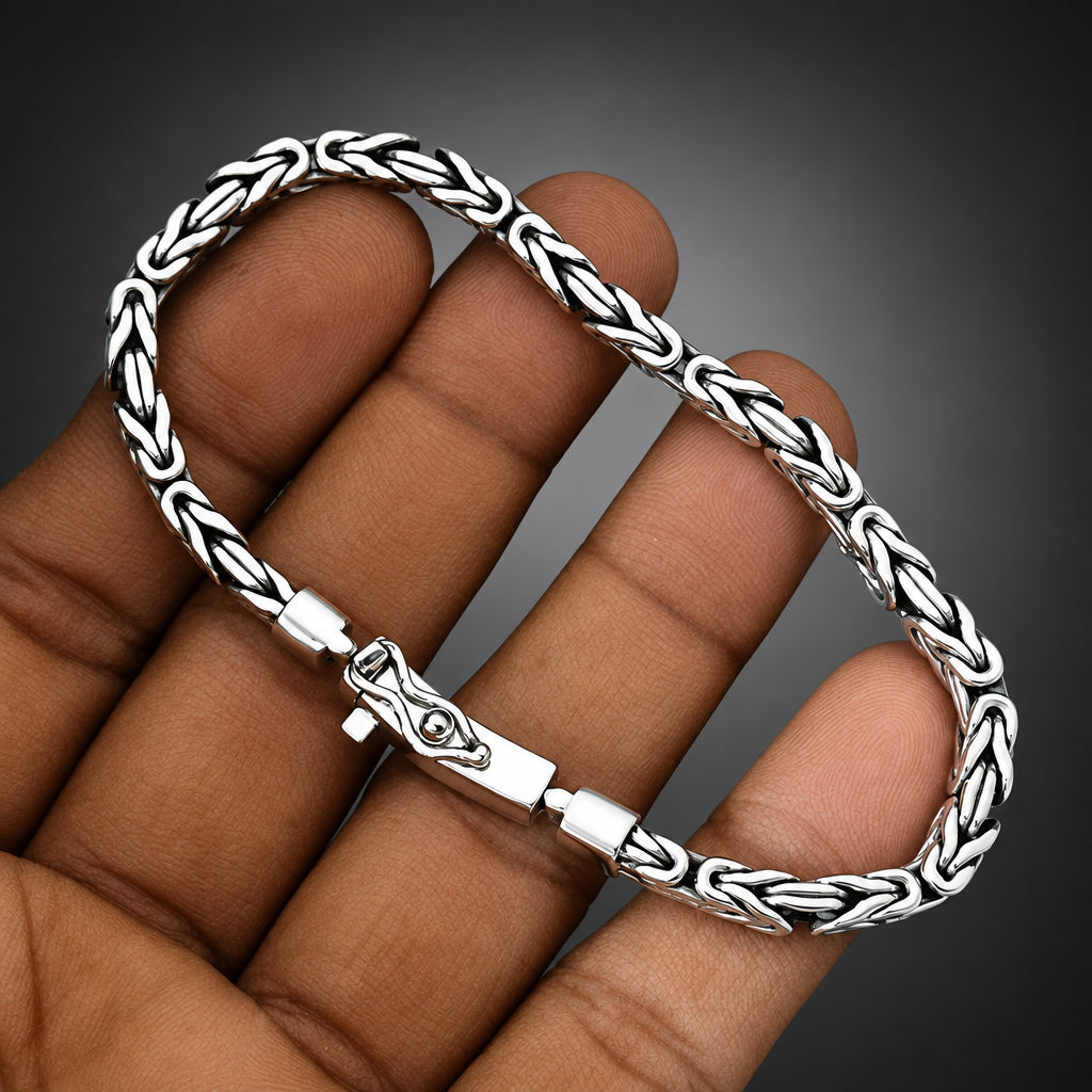 Silver braided bracelet on a hand against a gray background