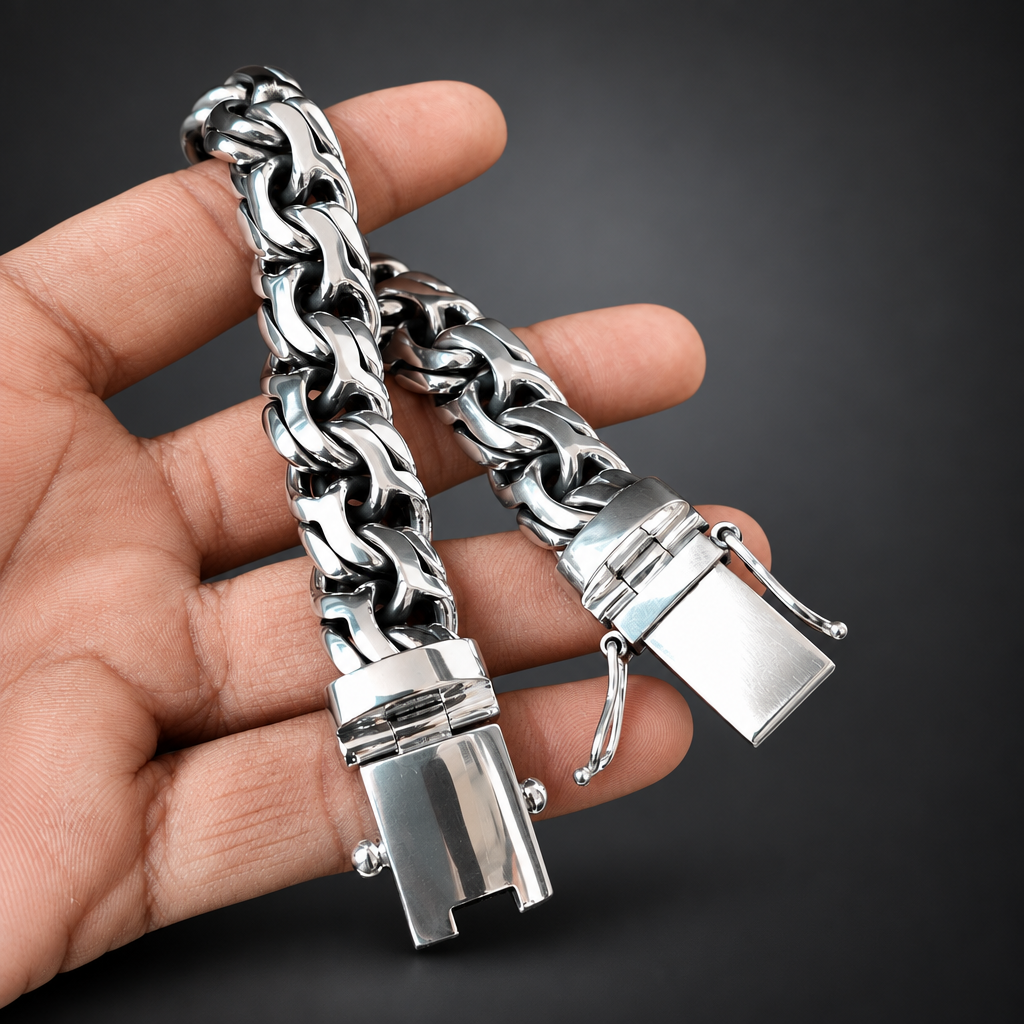 A silver-toned chunky chain bracelet with a unique lock clasp, held in a person's hand against a solid black background.
