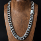 A thick silver Cuban link chain necklace displayed on a wooden neck bust against a black background.