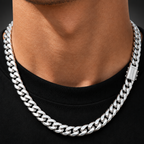 A close-up of a man's neck and chest wearing a thick, polished silver Cuban link chain necklace over a black t-shirt.