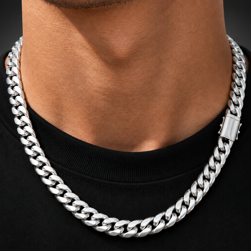 A close-up of a man's neck and chest wearing a thick, polished silver Cuban link chain necklace over a black t-shirt.