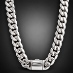 A chunky silver Cuban link chain necklace displayed on a dark wood bust, with a matching silver chain bracelet on a smaller wooden stand beside it, set against a neutral beige background.