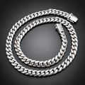 A silver-toned Cuban link chain necklace coiled on a black velvet fabric background.